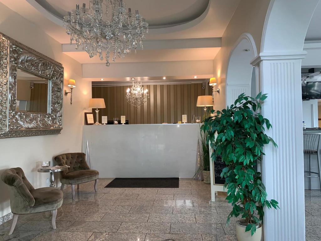 a lobby with chairs and a chandelier and a plant at Hotel zur Riede bei Bremen in Delmenhorst