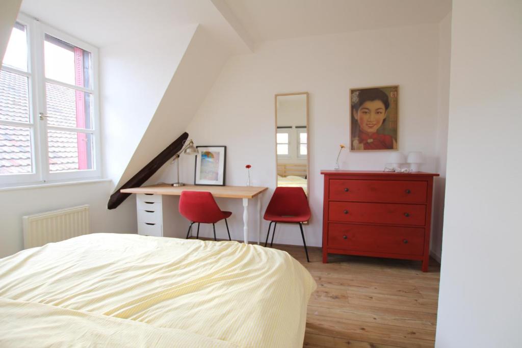 1 dormitorio con escritorio y 2 sillas rojas en Colmar City Center - Cosy Appartement BED' N' BREDALA Max, en Colmar