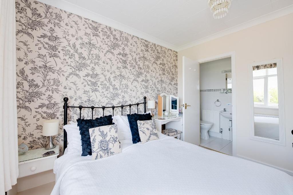 a bedroom with a white bed and a bathroom at The Coast Yard B & B and Garden Chalets in Selsey