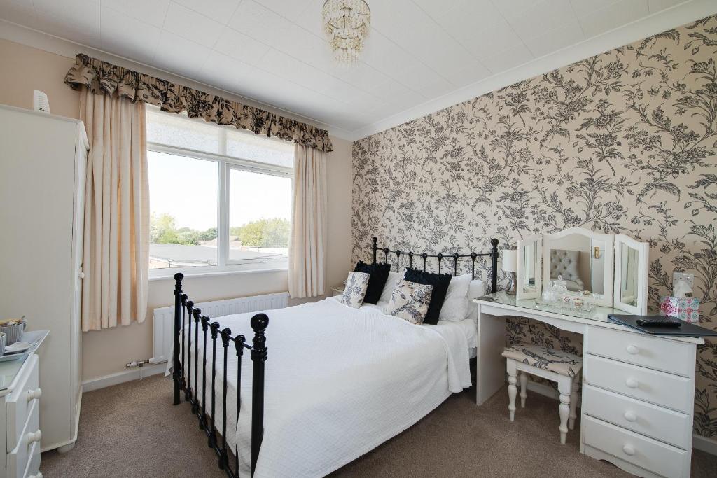 a bedroom with a bed and a desk and a window at The Coast Yard B & B and Garden Chalets in Selsey