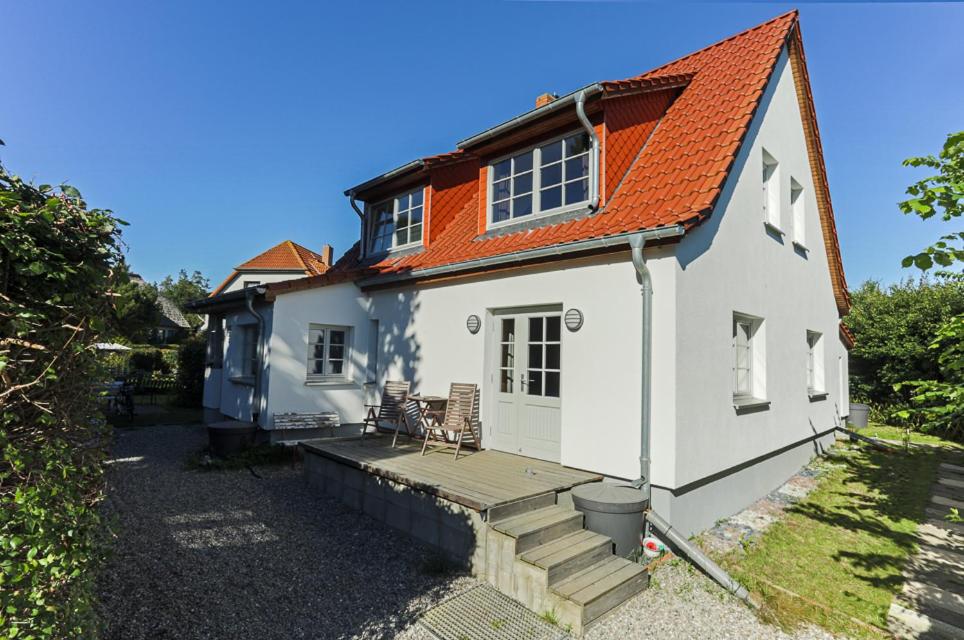 Casa blanca con techo naranja y terraza en Hügelhus en Kloster