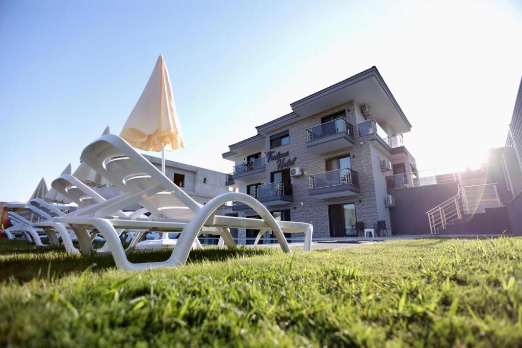 a row of white lawn chairs in front of a building at FONTANA HOTEL FENER in Çeşme