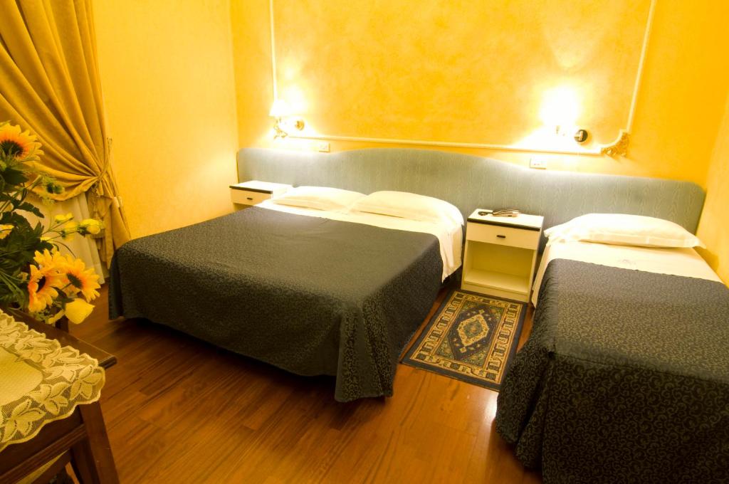 una camera d'albergo con due letti e due tavoli di Hotel Alba a Pescara