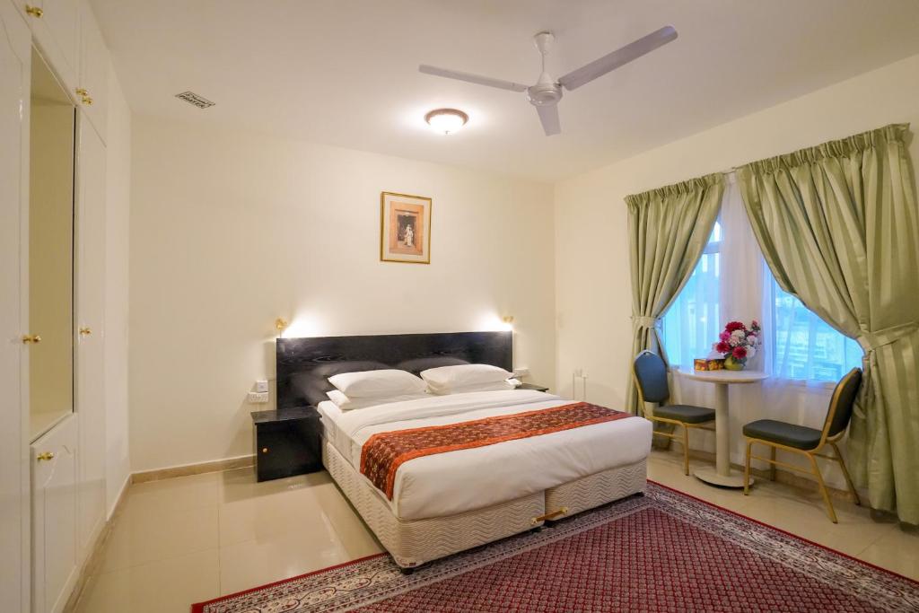 a bedroom with a bed and a table and chairs at Hotel Summersands Al Wadi Al kabir in Muscat