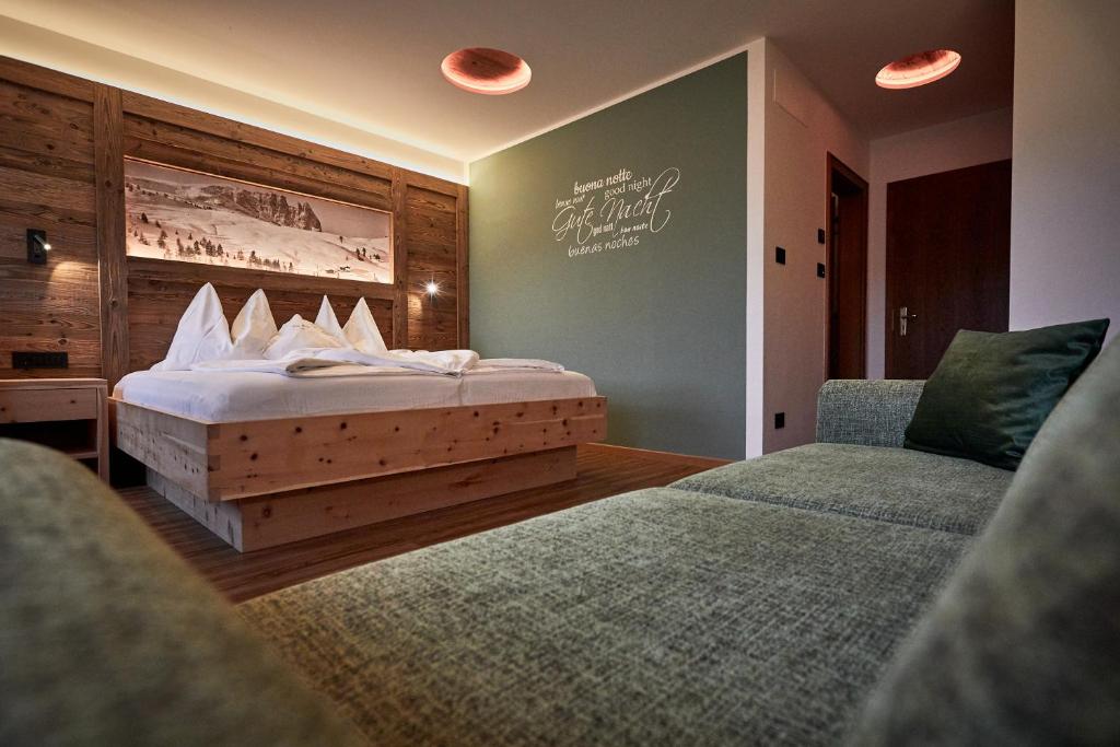 a bedroom with a bed and two chairs at Hotel Garnì Savoy in Castelrotto