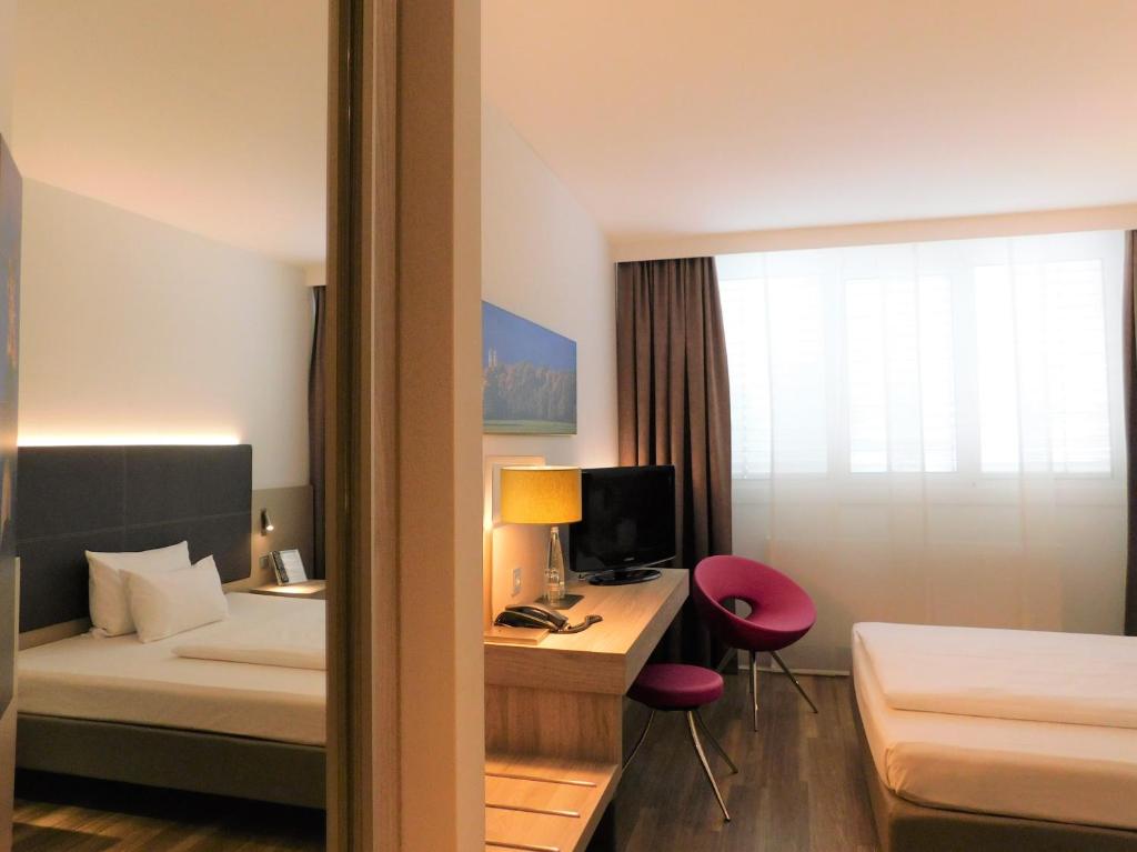 a hotel room with a bed and a desk with a computer at Feringapark Hotel Unterföhring in Munich