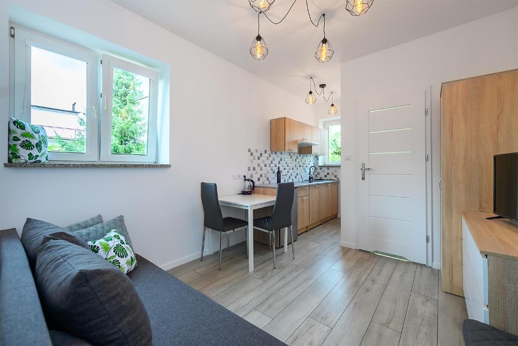 a living room with a couch and a table and a kitchen at Apartamenty Bałuty PARK in Łódź