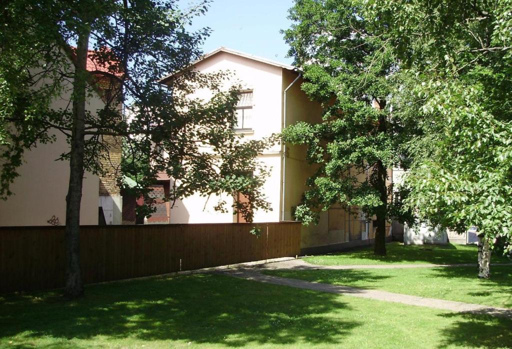 ein Haus mit einem Zaun und Bäumen im Hof in der Unterkunft Figaro in Ventspils