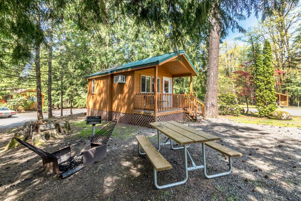 a cabin in the woods with a picnic table and a bench at Mount Hood Village Deluxe Cabin 5 in Welches