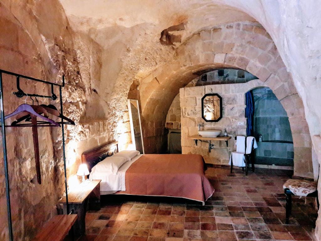 ein Schlafzimmer mit einem Bett in einem Steinzimmer in der Unterkunft Cave Rooms Sassi in Matera