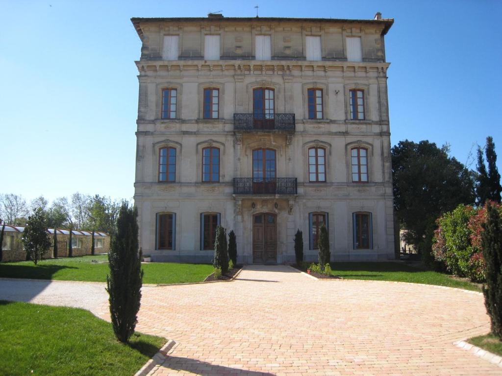 un grand bâtiment en pierre avec des arbres devant lui dans l'établissement Chateau Du Comte, à Saint-Nazaire-dʼAude