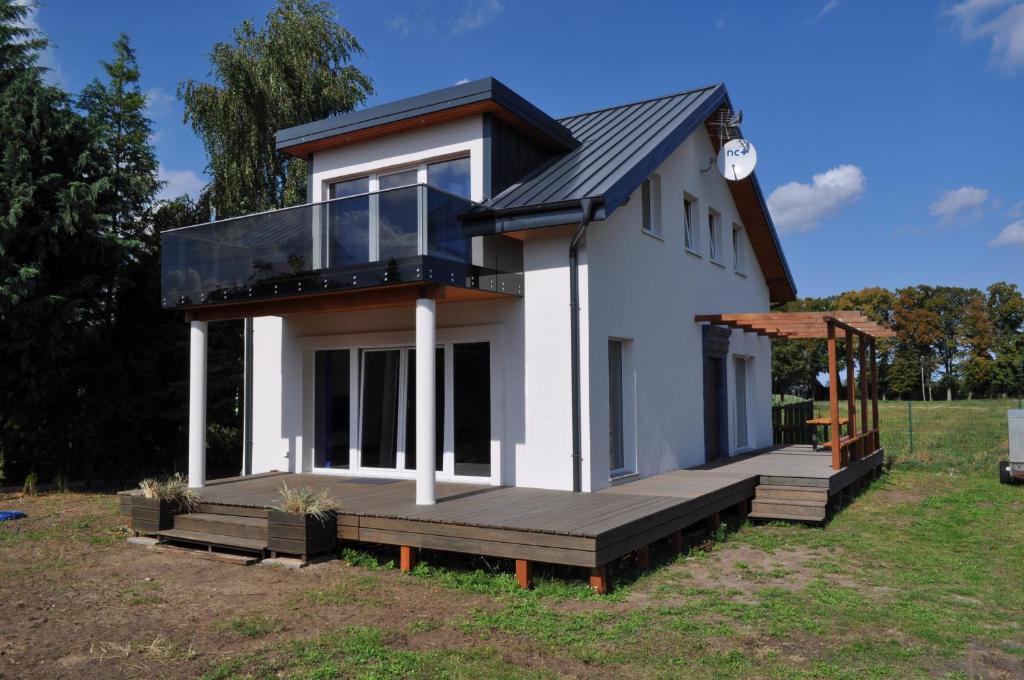 a small house with a large deck in a field at Villa Helena in Nowe Warpno