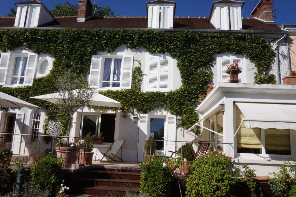 a white house with ivy on the facade at La Gallina Bianca in Feucherolles