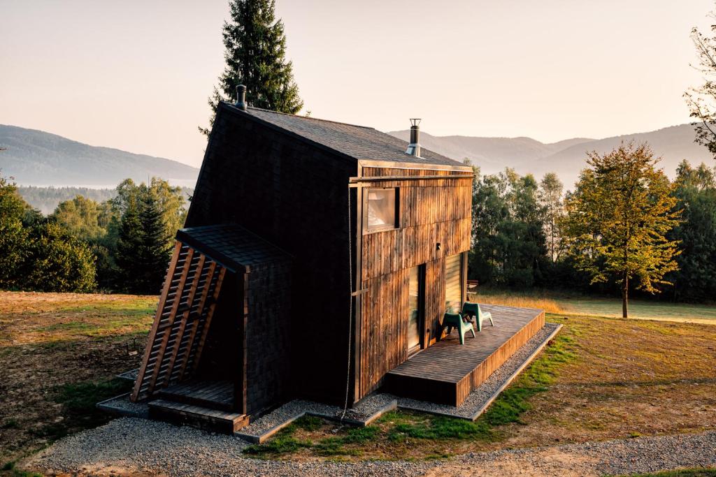 a tiny house with a staircase in a field at Domki 4 Nad Ranem - Baza Bieszczady Smerek in Wetlina