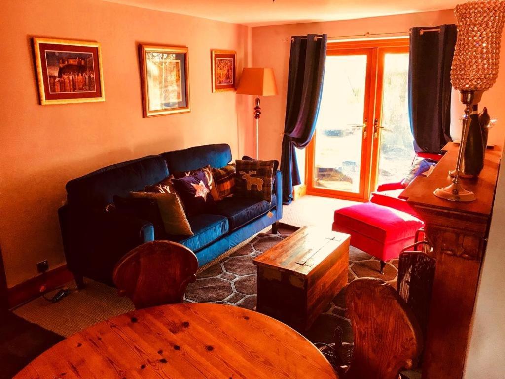a living room with a blue couch and a table at The Cottage, Grotton Hall, Lydgate, Saddleworth in Saddleworth