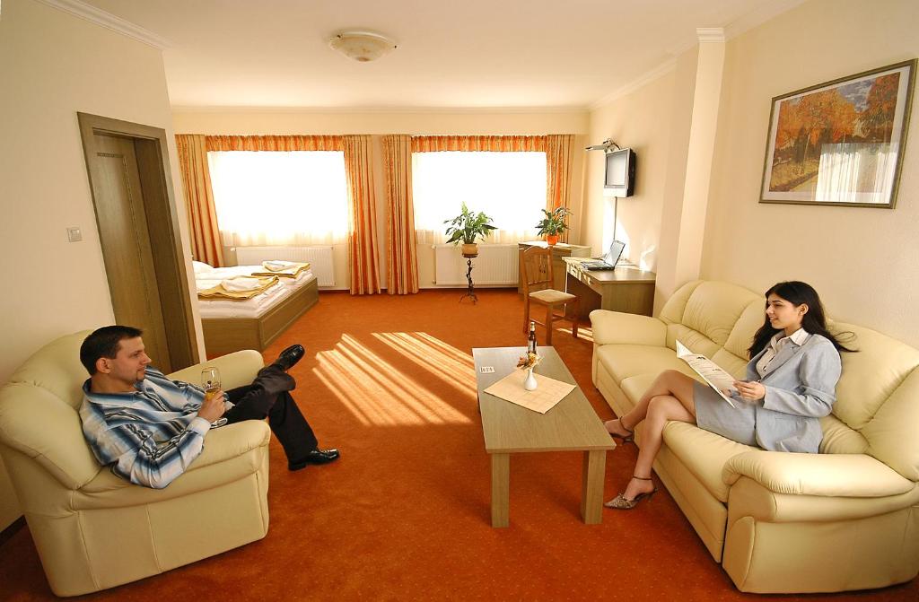 Hotel Bavaria في Abda: رجل وامرأة يجلسون في غرفة المعيشة