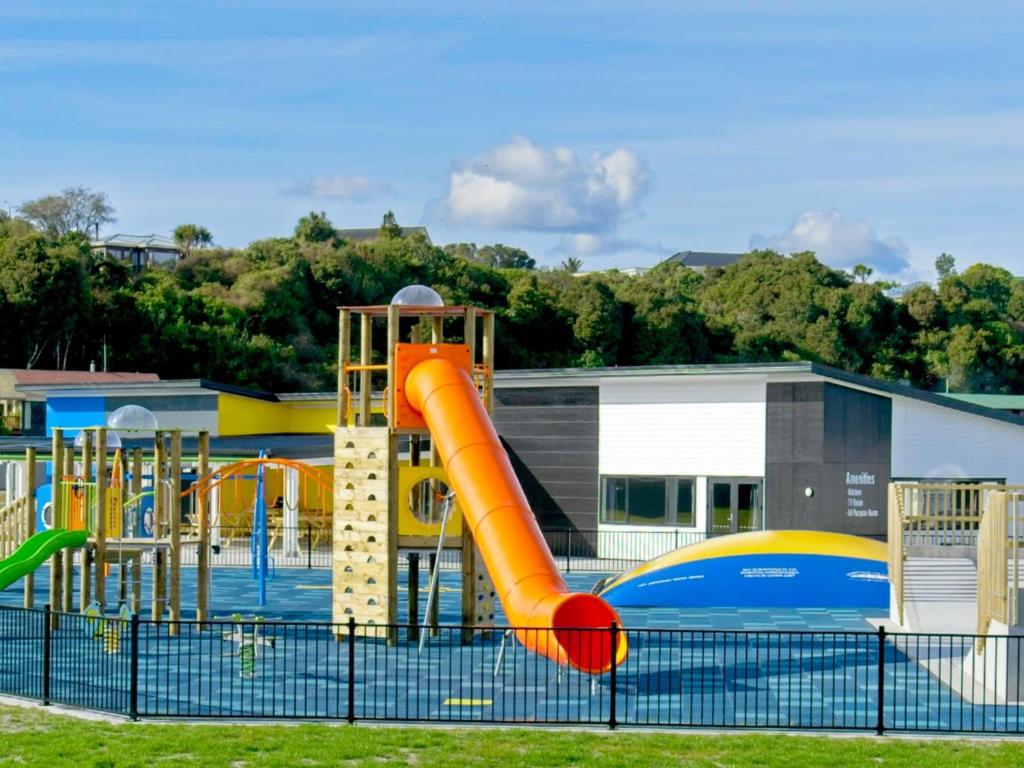 um parque infantil com um escorrega laranja num parque em Hokitika's Kiwi Holiday Park and Motels em Hokitika