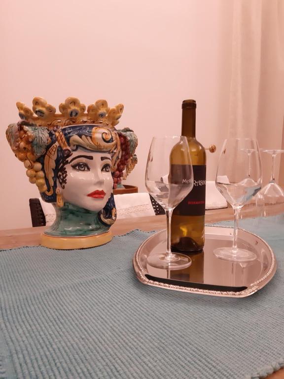 - une table avec une bouteille de vin et un vase dans l'établissement Happy Holiday, à Palazzolo Acreide