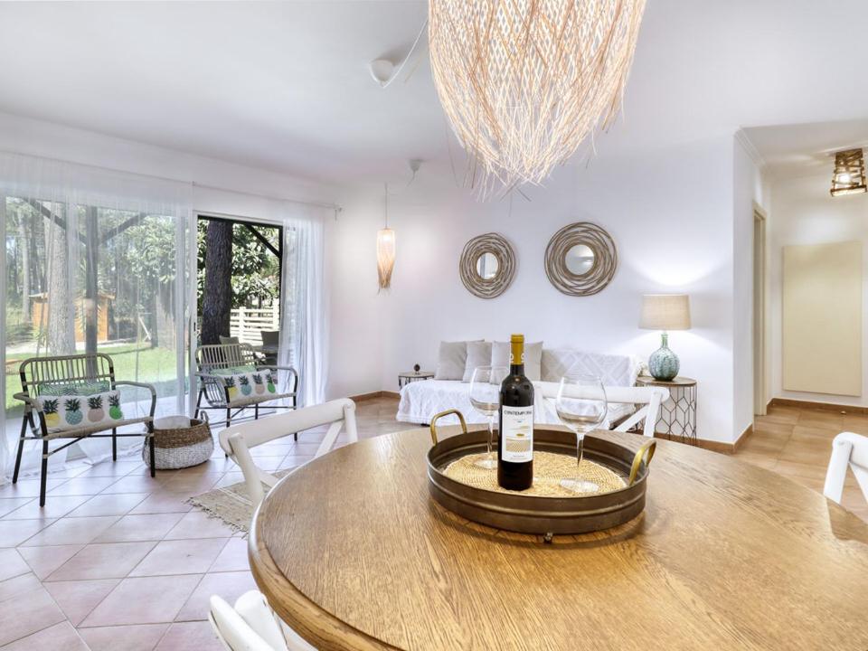 a living room with a table with a bottle of wine at Aroeira Golf - Beach House in Carcereiro