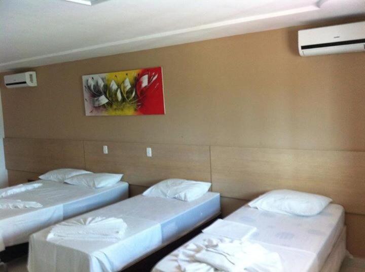 Habitación con 2 camas y una pintura en la pared. en Pousada Veraneio Ponta Negra, en Natal