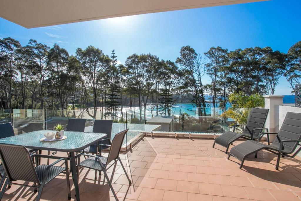 een patio met een tafel en stoelen en een zwembad bij Beach side holiday apartment in Batemans Bay
