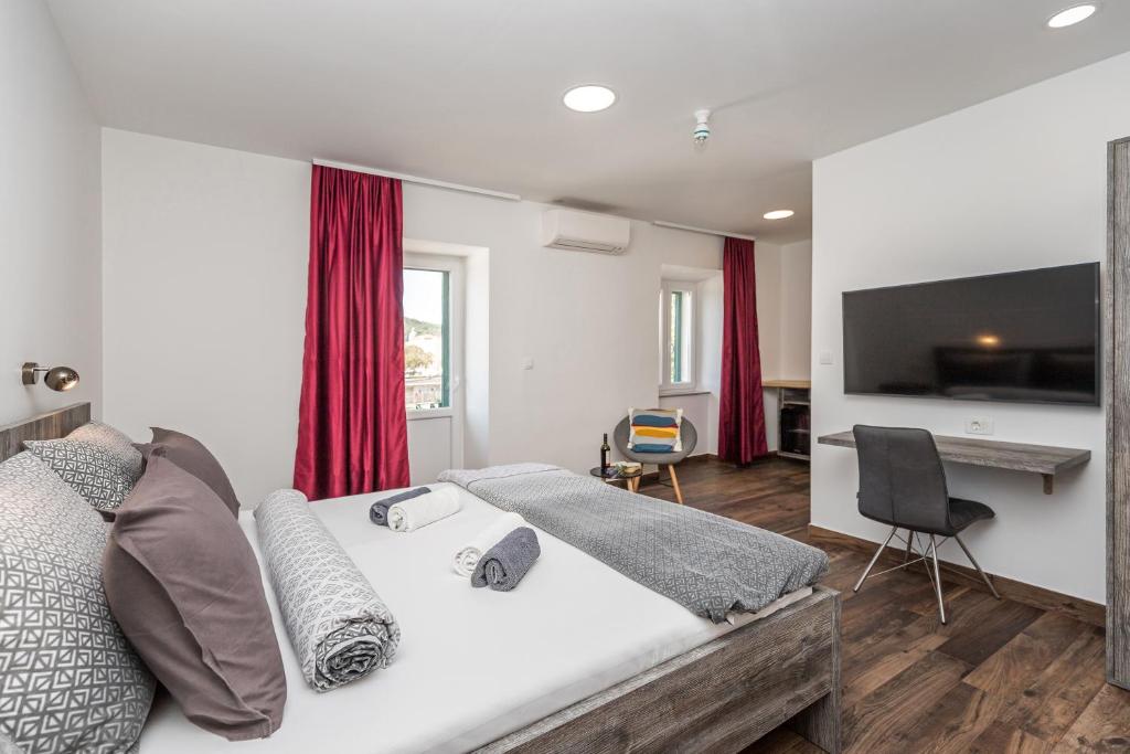 Schlafzimmer mit einem Bett und einem Schreibtisch mit einem TV in der Unterkunft Apinelo Port Rooms in Split