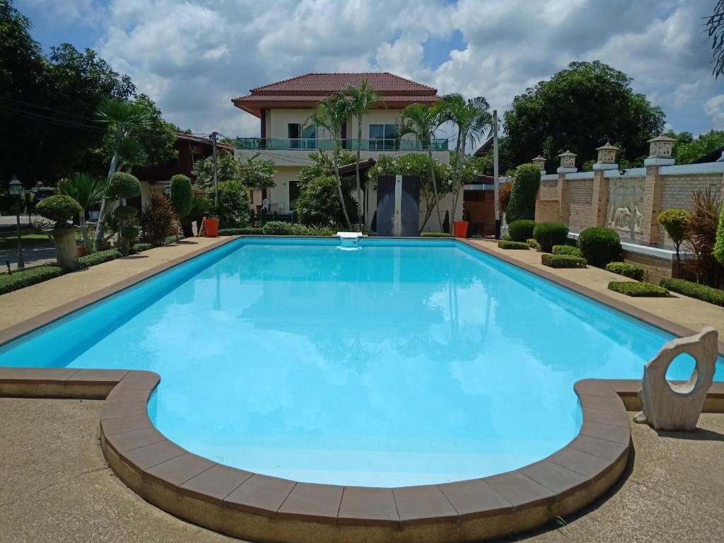 a large blue swimming pool with a house in the background at Sumali Villa in Sing Buri