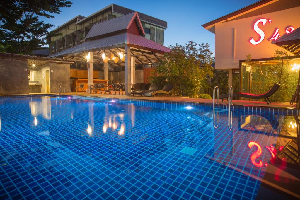A blue-tiled pool photographed at dusk beside the hotel buildings.