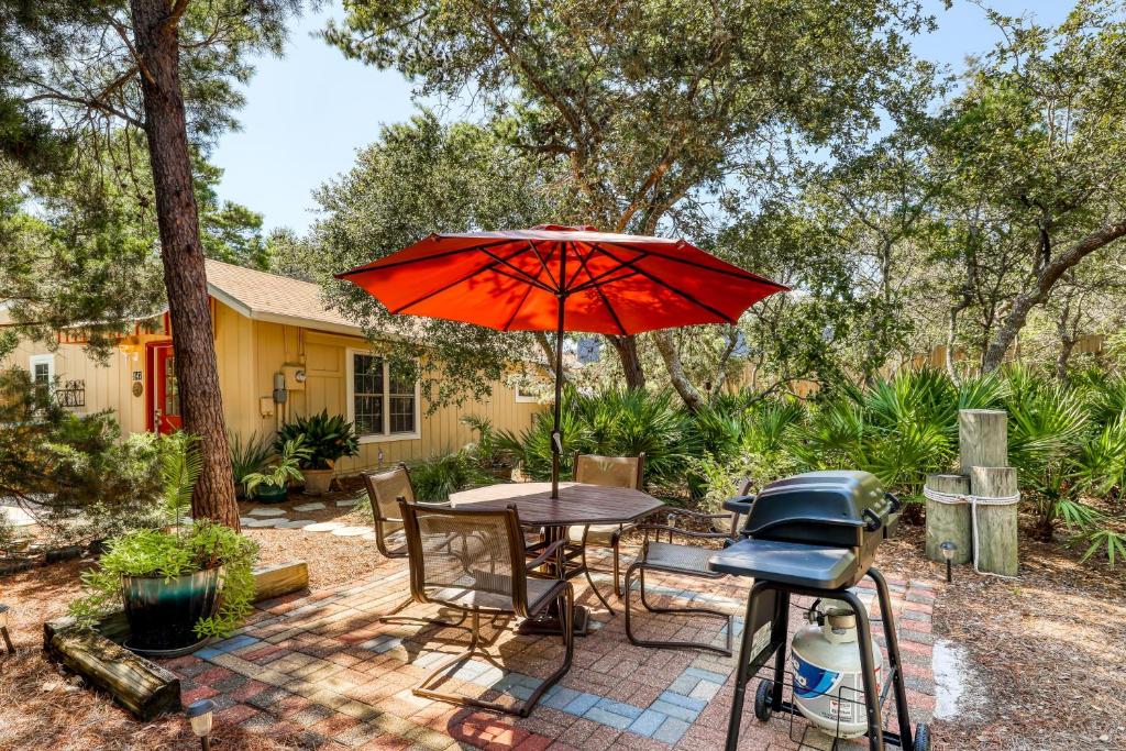 eine Terrasse mit Tisch und Stühlen und einem Sonnenschirm in der Unterkunft Sunshine Cottage in Santa Rosa Beach