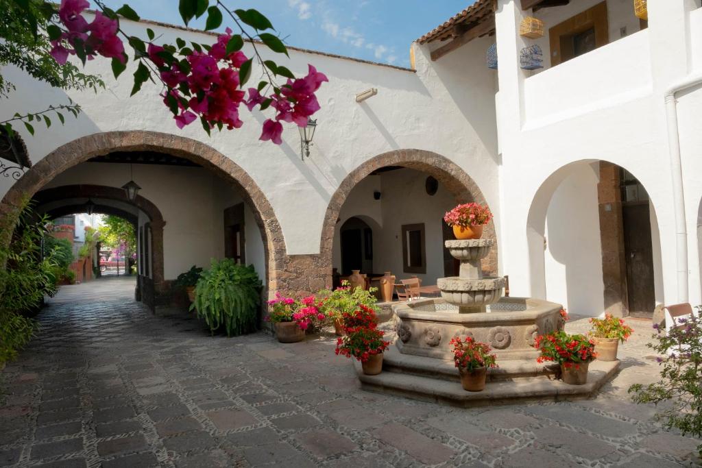 un patio con una fuente en un edificio con flores en Hotel Layseca en San Juan del Río