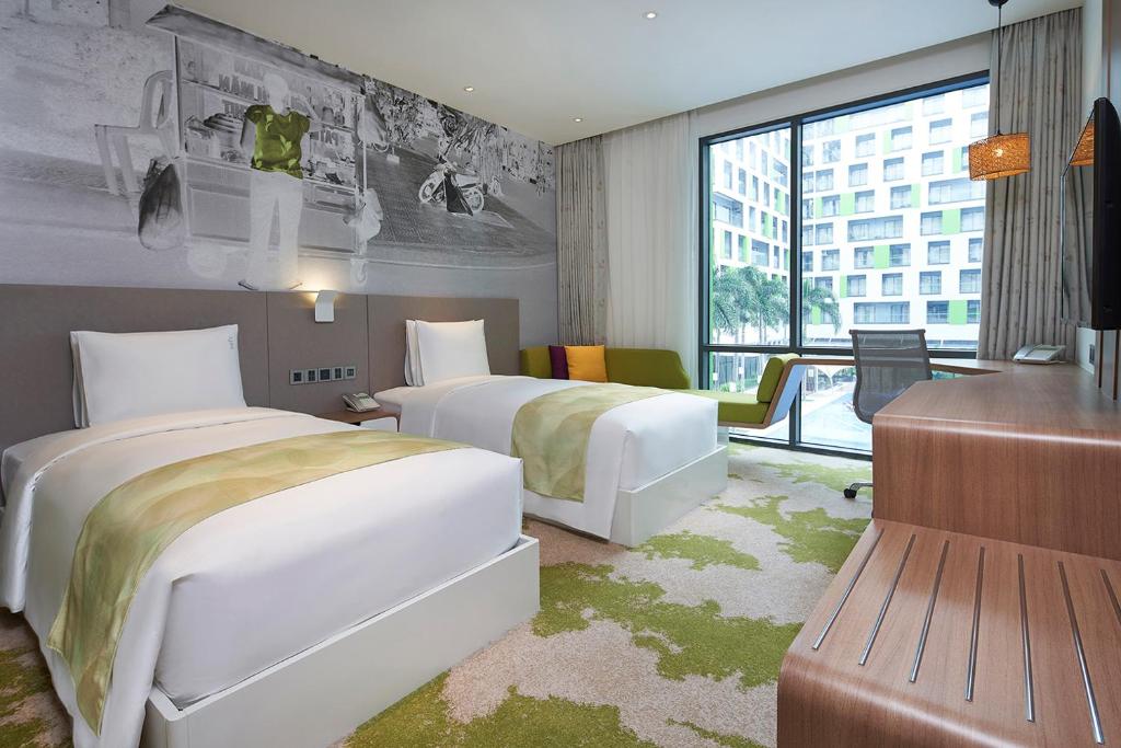 a hotel room with two beds and a desk at Holiday Inn & Suites Saigon Airport by IHG in Ho Chi Minh City