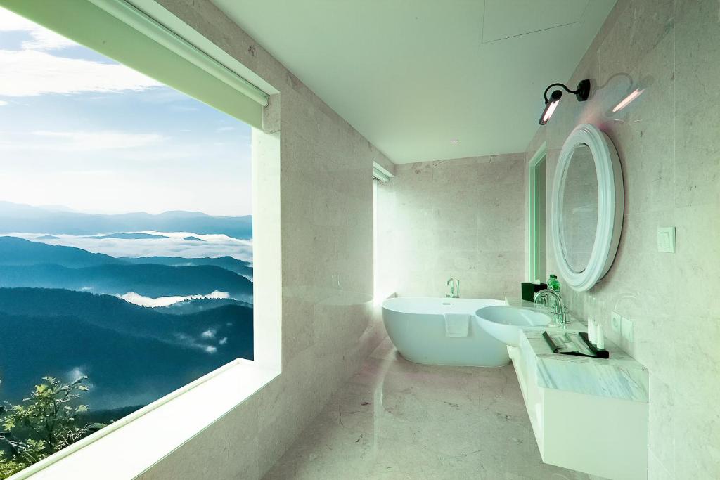 a bathroom with a tub and a sink and a window at De Paviljoen Bandung in Bandung