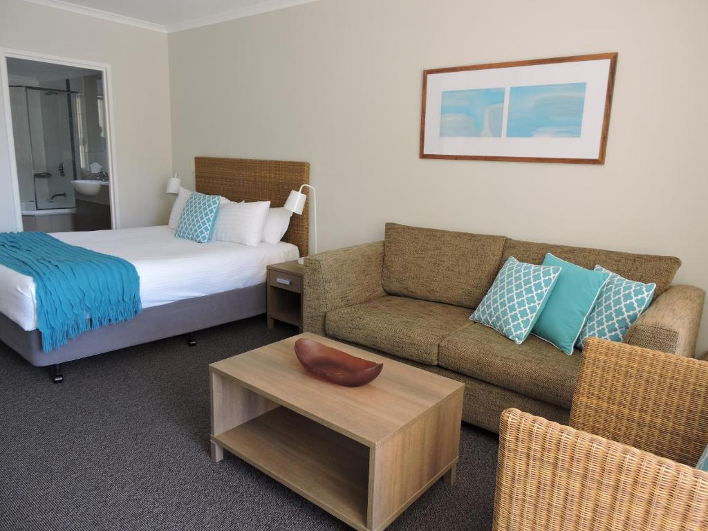 um quarto de hotel com uma cama, um sofá e uma mesa em BASE Holidays - Ettalong Beach Premium Apartments em Ettalong Beach