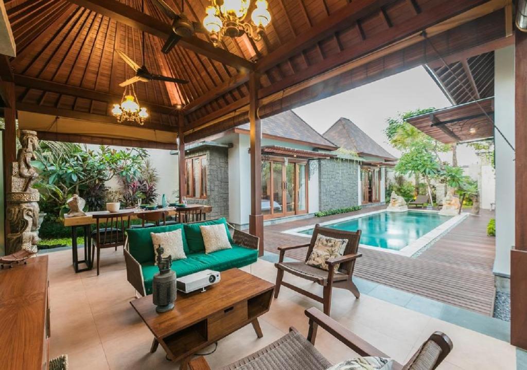ein Wohnzimmer im Freien mit einer grünen Couch und einem Pool in der Unterkunft Villa Niketan Sanur - Three bedroom, Sanur, Near Icon Mall, Harbor in Sanur