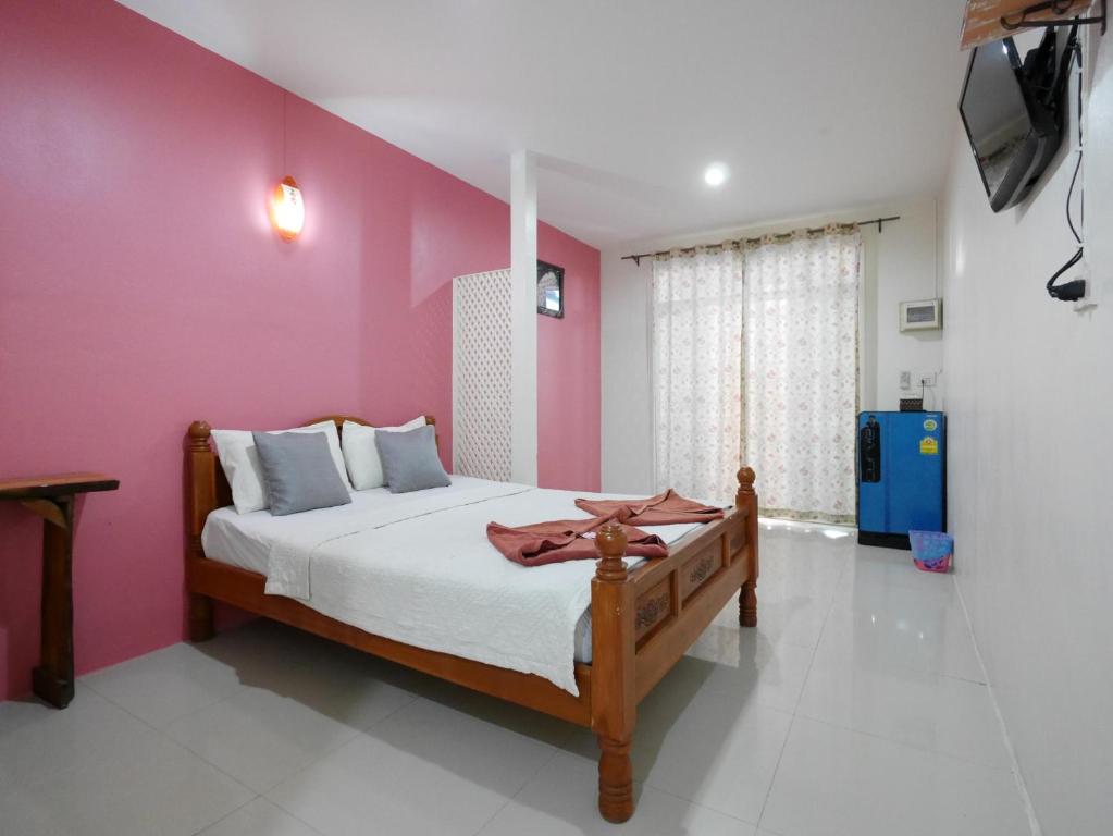 1 dormitorio con cama y pared de color rosa en Ban FahSai Guest House, en Ko Samed