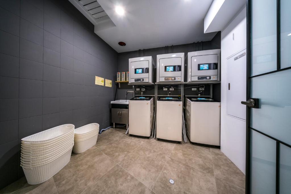 a laundry room with three washers and three machines at Watermark Hotel - Sizihwan in Kaohsiung