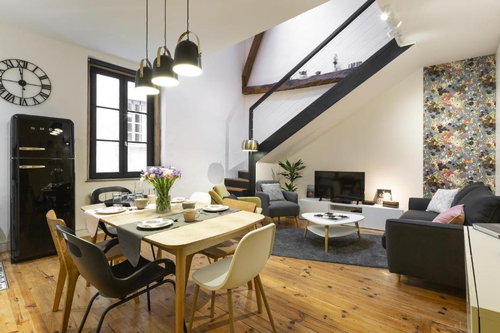 een eetkamer en een woonkamer met een tafel en stoelen bij La Sonate by Cocoonr in Rennes