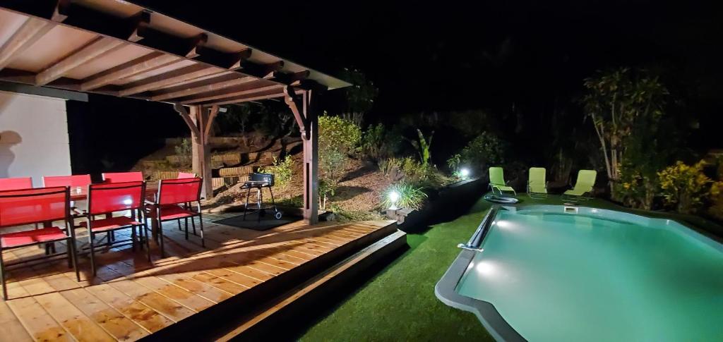 a backyard with a swimming pool at night at La Maison Dakoté in Sainte-Clotilde