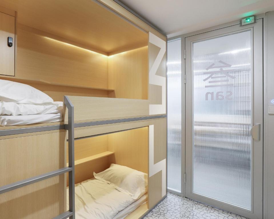 a small room with a bunk bed and a glass door at WeFlow Hostel (Shanghai Xintiandi) in Shanghai