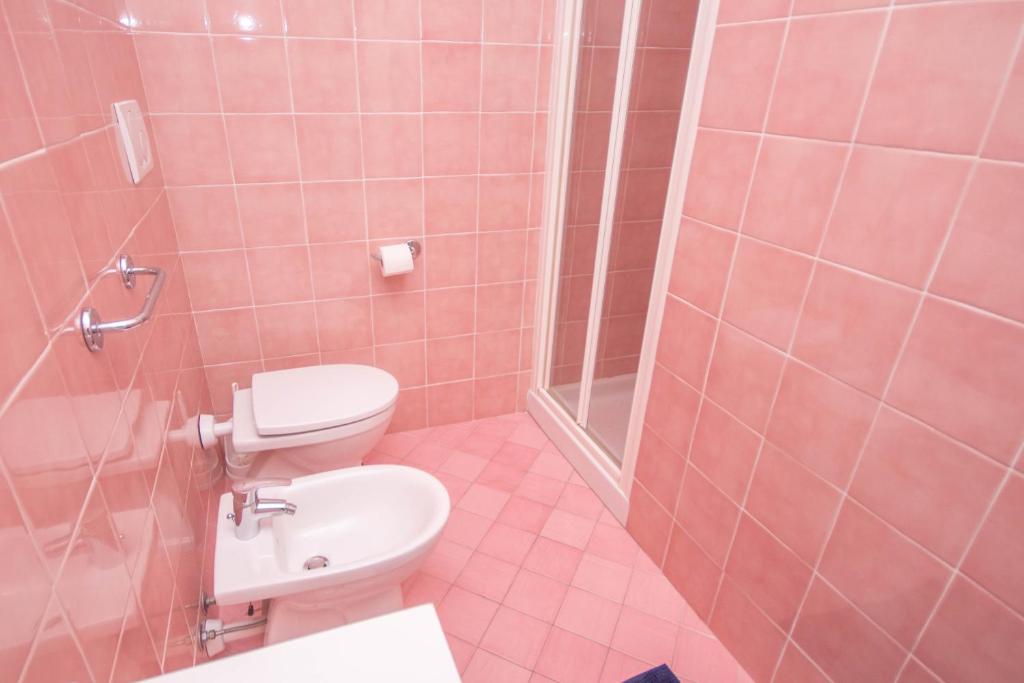 różowa łazienka z toaletą i prysznicem w obiekcie Le Saline w mieście Portoferraio