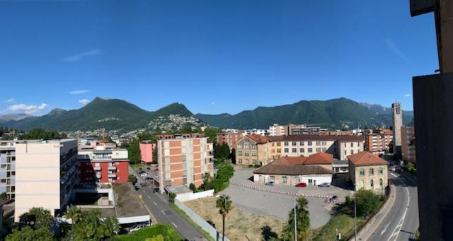 una ciudad con edificios y montañas en el fondo en Karl&Deby Lugano stazione/centro en Lugano