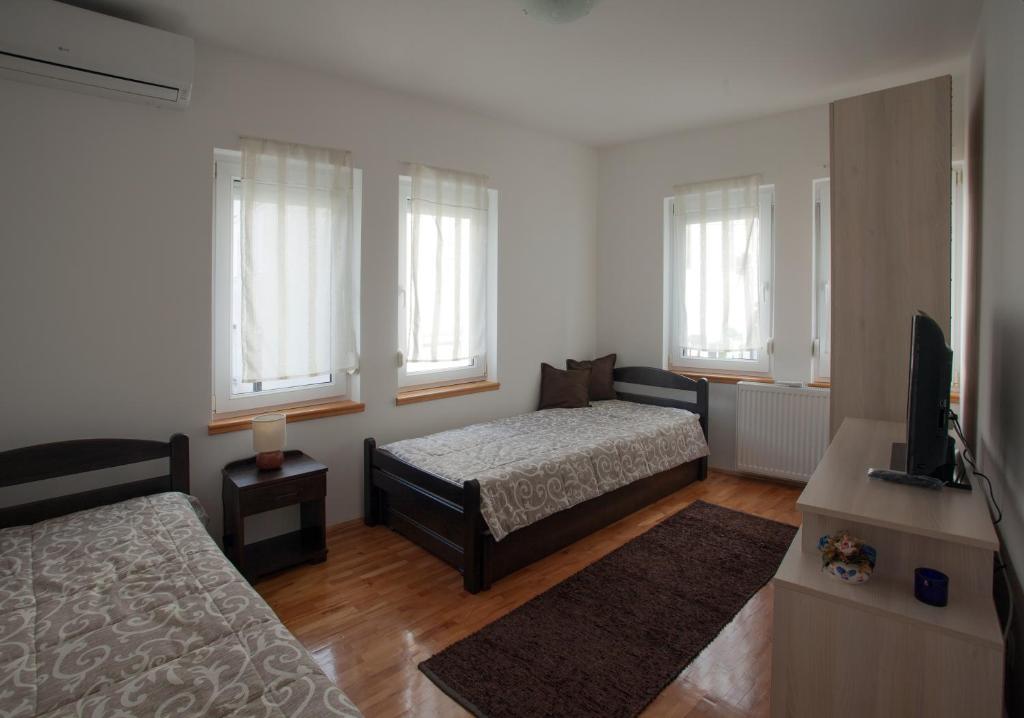 a bedroom with two beds and a flat screen tv at Guesthouse Rota in Mostar