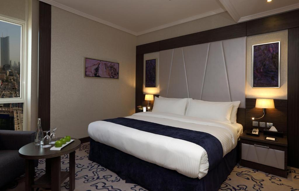 a hotel room with a large bed and a chair at Swiss Flora Royal Hotel Riyadh in Riyadh