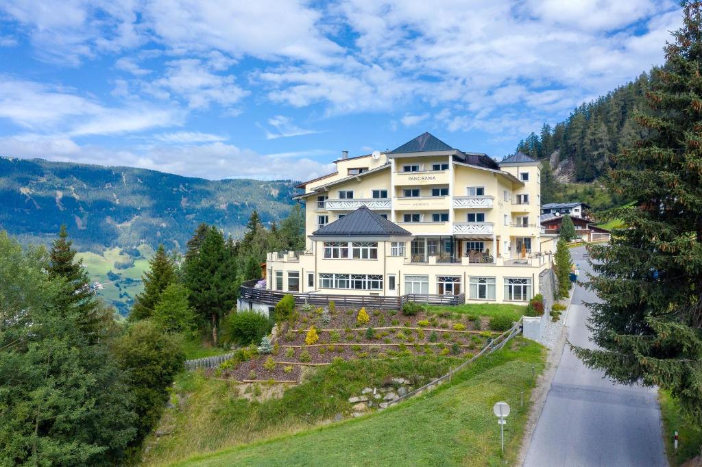 una grande casa bianca sul ciglio di una strada di Wellness Aparthotel Panorama Alpin - Ferienwohnungen Jerzens im Pitztal a Jerzens