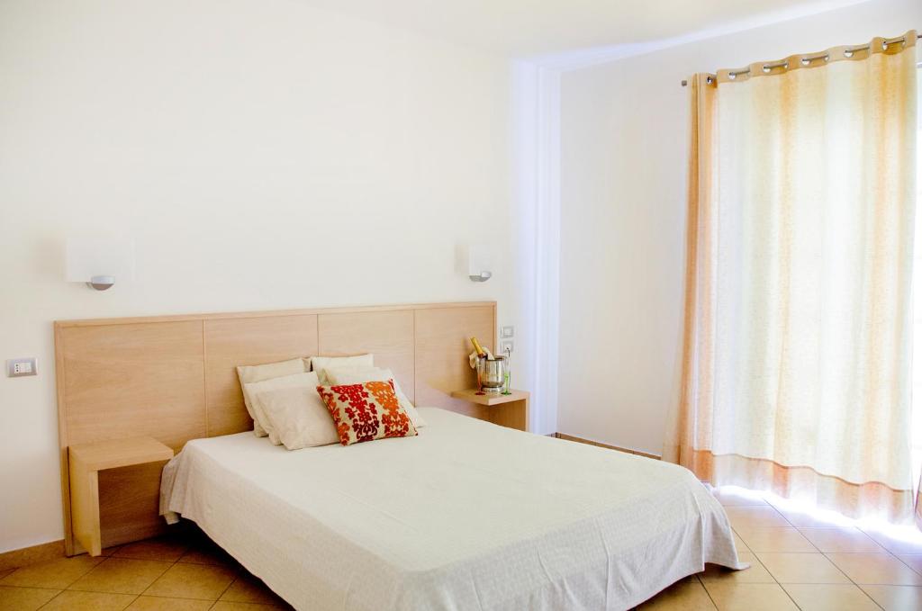 Schlafzimmer mit einem weißen Bett mit einem Kopfteil aus Holz in der Unterkunft Hotel Garden in Praia a Mare