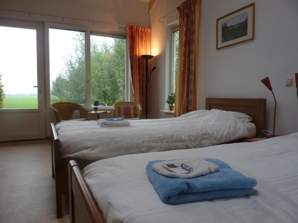 a hotel room with three beds with towels on them at Boerderij "De Verwondering" in Goudriaan