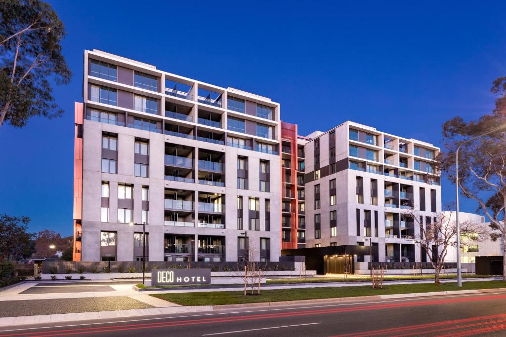 two tall white buildings next to a street at Deco Hotel Canberra in Canberra