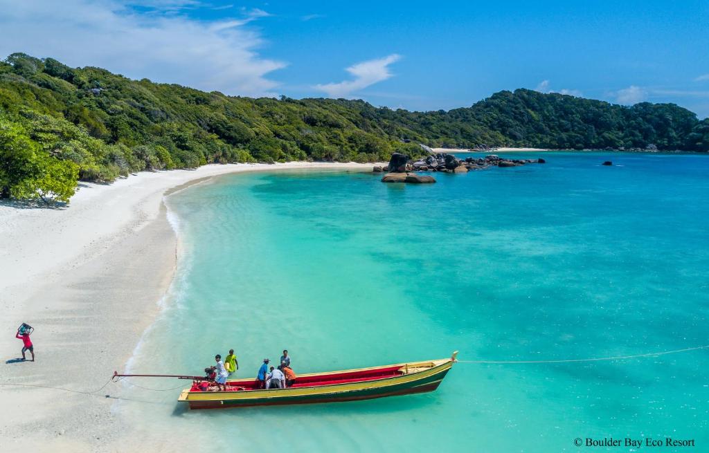 un grupo de personas en un barco en una playa en Boulder Bay Eco Resort - Nga Khin Nyo Gyee Island, en Nga Khin Nyo Gyee Island