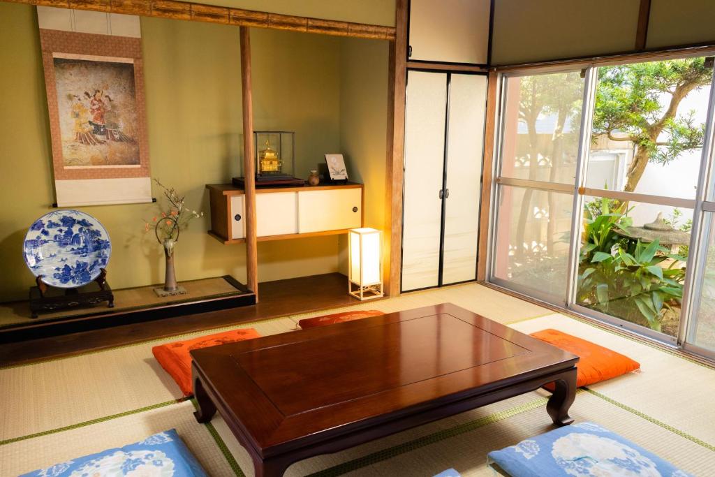 sala de estar con mesa de centro y ventana grande en Guesthouse Hajimari, en Kashihara