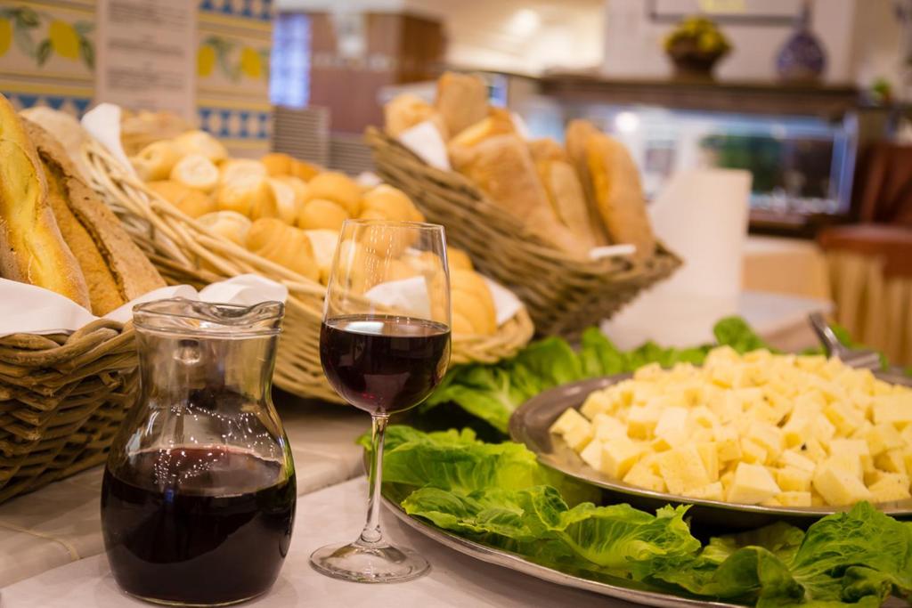 a glass of red wine next to a plate of bread at Hotel Olimpo le Terrazze in Letojanni